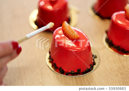 chef decorating glaze cakes at pastry shop 33930983