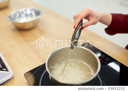 chef measuring temperature in syrup at kitchen chef measuring temperature in syrup at kitchen 33931252