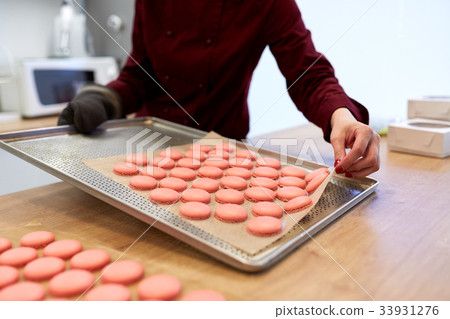 chef with macarons on oven tray at confectionery chef with macarons on oven tray at confectionery 33931276