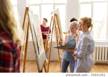 artists discussing painting on easel at art school artists discussing painting on easel at art school 33931301