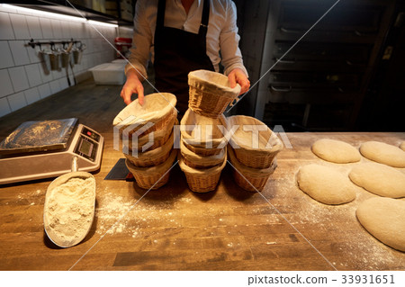 baker with baskets for dough rising at bakery 33931651