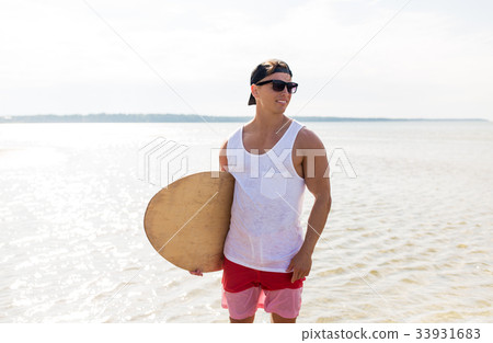 happy young man with skimboard on summer beach 33931683
