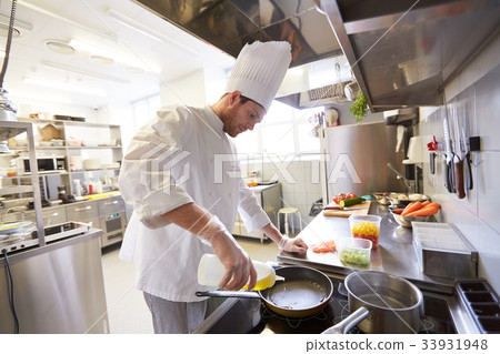happy male chef cooking food at restaurant kitchen happy male chef cooking food at restaurant kitchen 33931948
