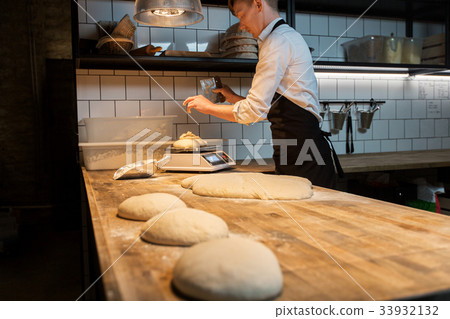 chef or baker weighing dough on scale at bakery 33932132