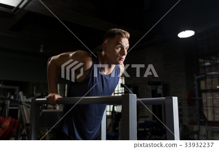 man doing triceps dip on parallel bars in gym man doing triceps dip on parallel bars in gym 33932237