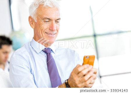 Businessman at the office with mobile phone Businessman at the office with mobile phone 33934143