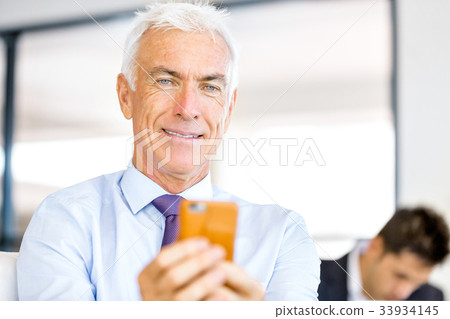 Businessman at the office with mobile phone 33934145