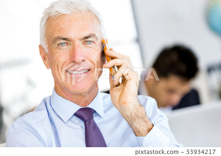 Businessman at the office with mobile phone Businessman at the office with mobile phone 33934217