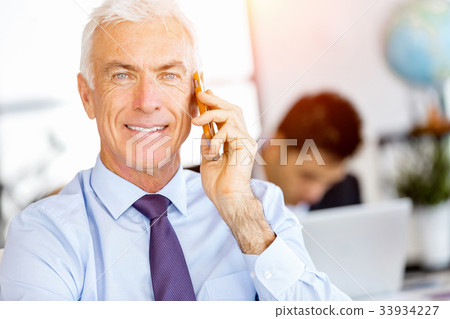 Businessman at the office with mobile phone Businessman at the office with mobile phone 33934227