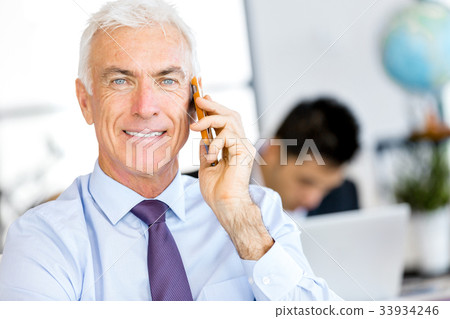 Businessman at the office with mobile phone Businessman at the office with mobile phone 33934246