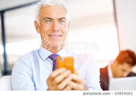Businessman at the office with mobile phone Businessman at the office with mobile phone 33934261