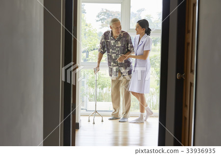 a nurse is assisting old man to walking with cane indoors 33936935