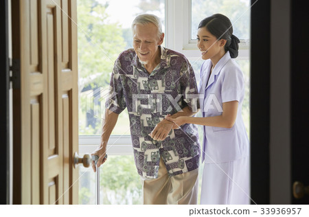 a nurse and senior man are smiling and walking indoors a nurse and senior man are smiling and walking indoors 33936957