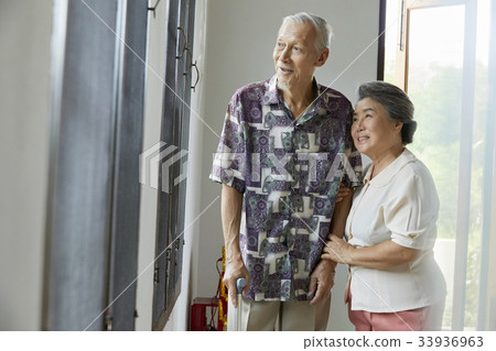 senior couple is standing and looking at something from window senior couple is standing and looking at something from window 33936963