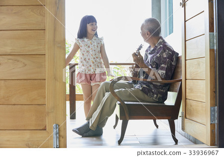 senior man is playing guitar and his granddaughter is singing 33936967