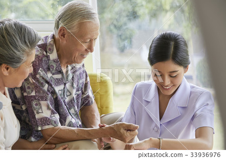 a nurse is checking the pulse of senior patient 33936976