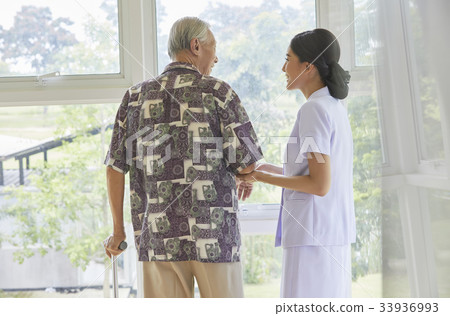 A senior man is standing with the help of the nurse 33936993