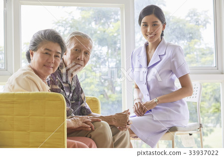 A senior couple and a nurse are sitting and smiling 33937022