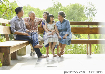 An extended family is talking happily while sitting on the bench. 33937098