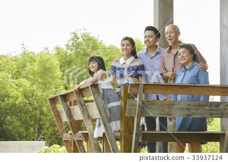 an extended family is standing, smiling and looking at something outside. an extended family is standing, smiling and looking at something outside. 33937124