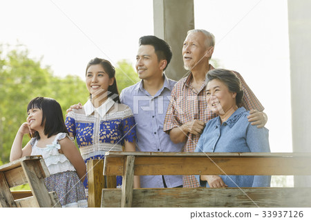 an extended family is standing side by side and looking at something. 33937126