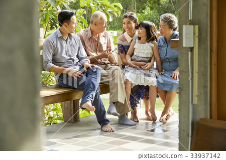 an extended family is sitting on a bench, talking and smiling 33937142