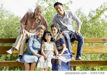 an extended family is sitting on the bench and looking at camera an extended family is sitting on the bench and looking at camera 33937169