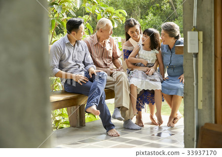 an extended family is sitting on the bench and smiling happily 33937170