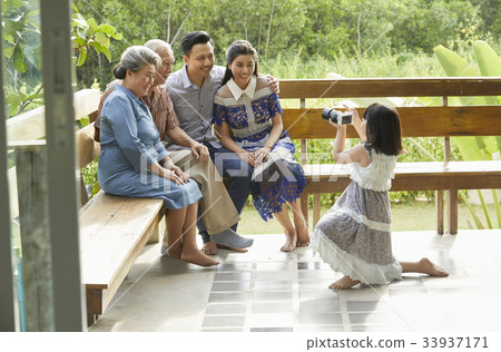 a child is holding a camera and taking photos of her family a child is holding a camera and taking photos of her family 33937171