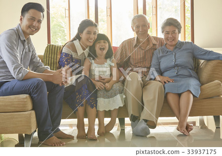 an extended family is sitting inside of the house and smiling happily an extended family is sitting inside of the house and smiling happily 33937175