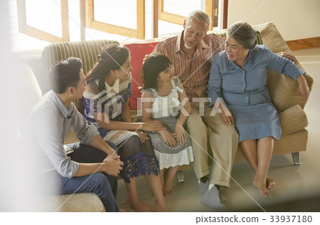 an extended family is sitting on a sofa and talking an extended family is sitting on a sofa and talking 33937180