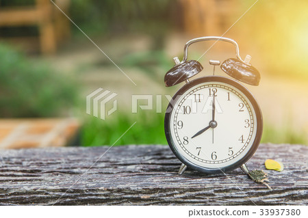 clock on wood table with green nature background clock on wood table with green nature background 33937380