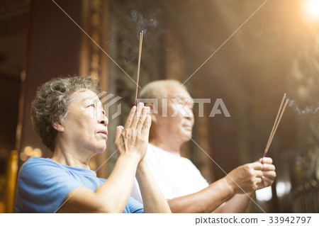 senior couple praying buddha with incense stick  33942797