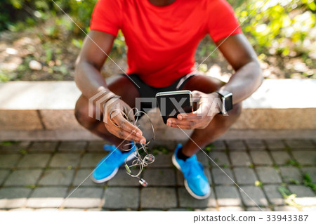 Unrecognizable runner with smart phone, listening 33943387