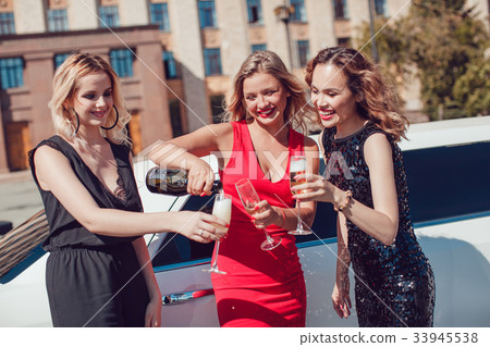 Beautiful women near the limousine have fun and 33945538