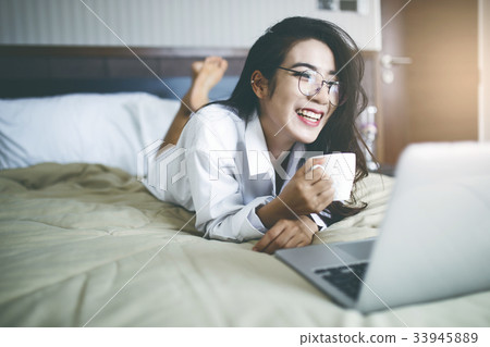 Happy asia woman working on bed with laptop . Happy asia woman working on bed with laptop . 33945889