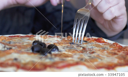 Male hands slicing pizza with ham, olives, cheeze 33947105