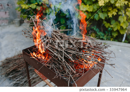 Burning dry branches in the brazier. 33947964
