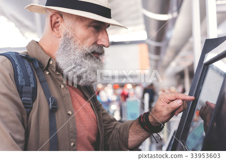 Serious old man typing on cash machine 33953603