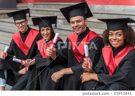Glad young students sitting on steps in graduation 33953841