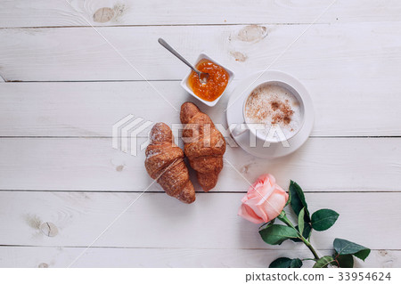Coffee mug with croissant,rose, jam on table 33954624