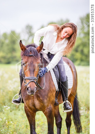 Young rider girl bent to horse for complimenting 33955378