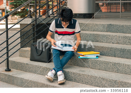 fashion guy reads books sitting on the street 33956118