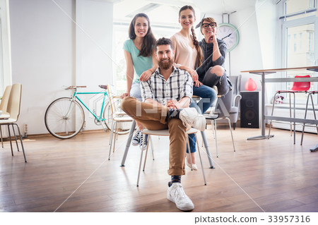 four co-workers wearing casual clothes during work 33957316