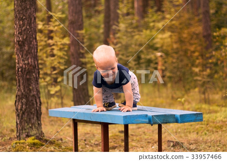 Cute smirking toddler playing on the bench in the 33957466