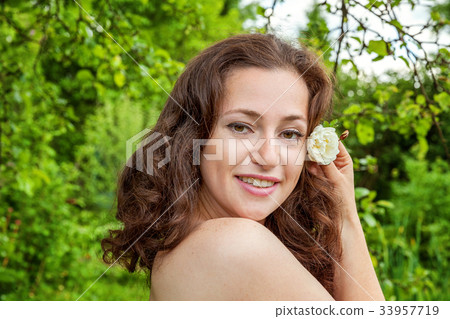Girl with the flower in her hand in a park 33957719