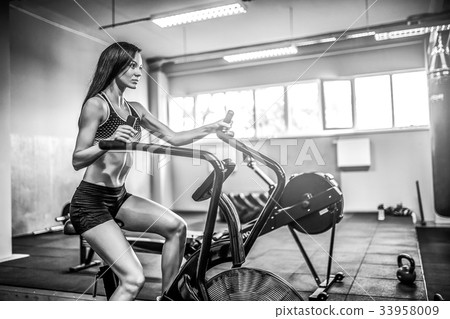Fitness female using air bike for cardio workout Fitness female using air bike for cardio workout 33958009