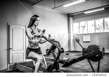 Fitness female using air bike for cardio workout Fitness female using air bike for cardio workout 33958010