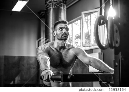 Strong muscular man doing push-ups on uneven bars Strong muscular man doing push-ups on uneven bars 33958164