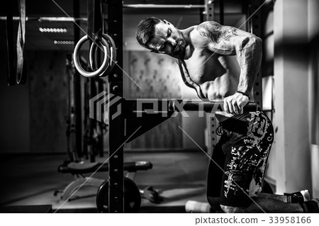 Strong muscular man doing push-ups on uneven bars Strong muscular man doing push-ups on uneven bars 33958166